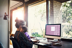 A mother at home browsing the internet on her home computer.